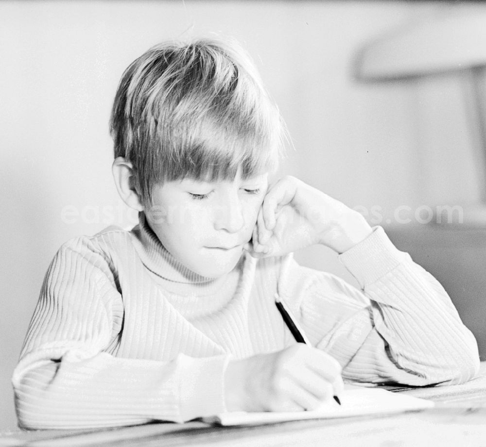 GDR photo archive: Berlin - A boy writes with a pen on a piece of paper in Berlin, the former capital of the GDR, German Democratic Republic