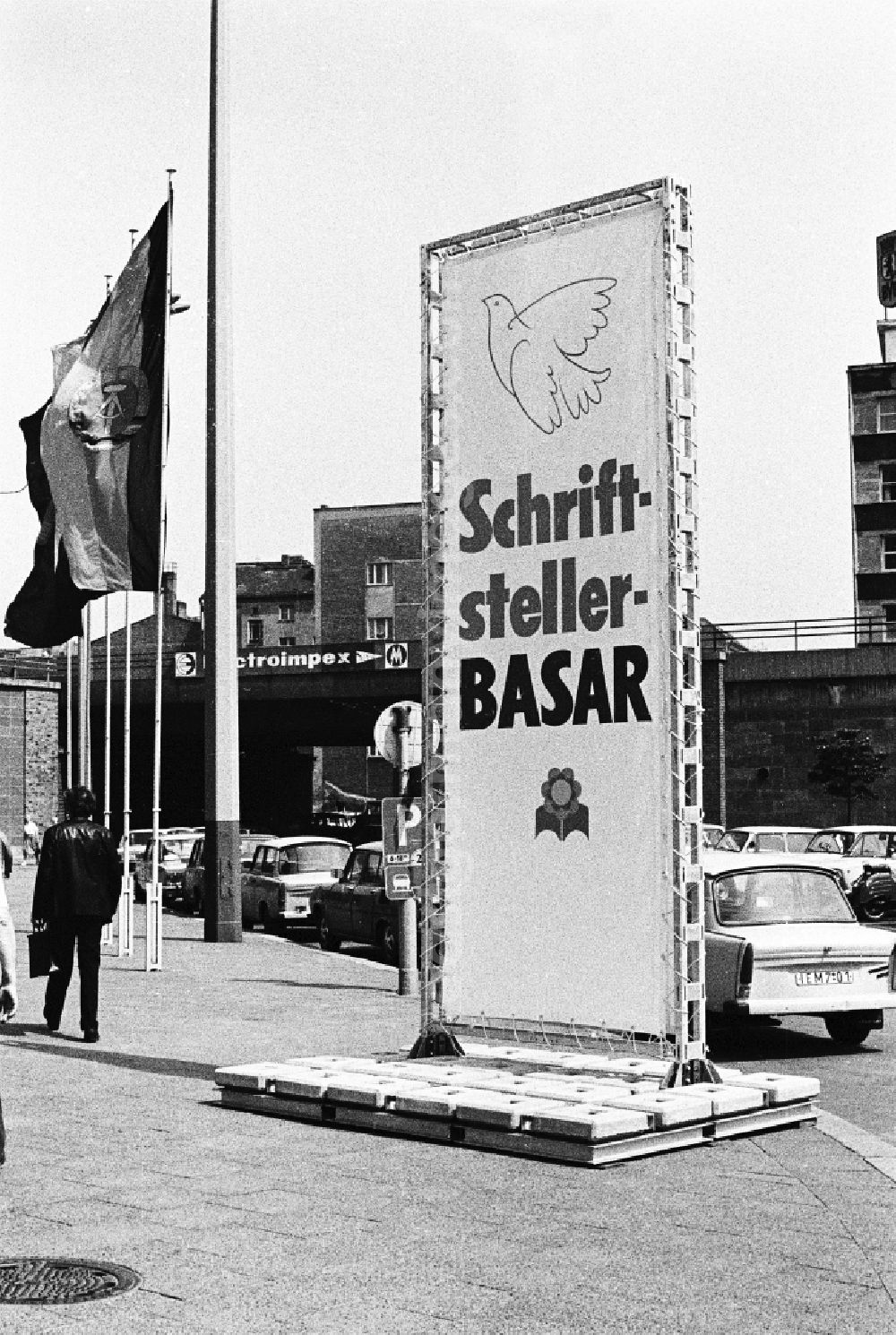 GDR image archive: Berlin - Advertising board with the inscription Writers' Bazaar on the occasion of the National Youth Festival in East Berlin on the territory of the former GDR, German Democratic Republic. Trabant cars are parked on the side of the road