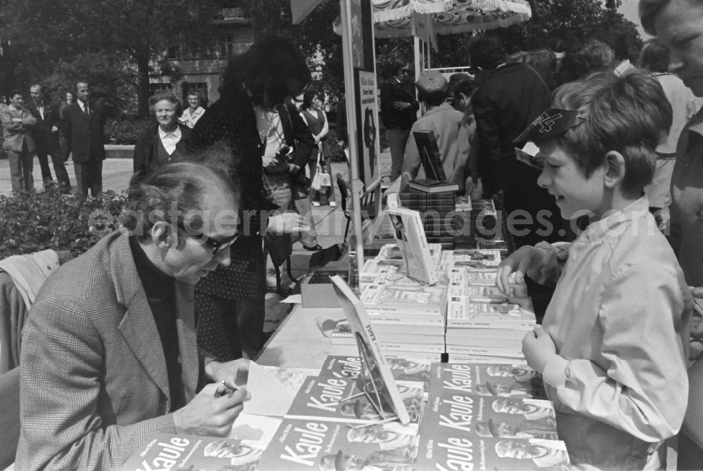 GDR image archive: Erfurt - Writers' bazaar on the grounds of the IGA in the Rose Garden on the occasion of the 15th Workers' Festival in Erfurt in the federal state of Thuringia in the territory of the former GDR, German Democratic Republic. Alfred Wellm ( known in the GDR mainly as a children's author ) signs his book Kaule for a boy at the book bazaar