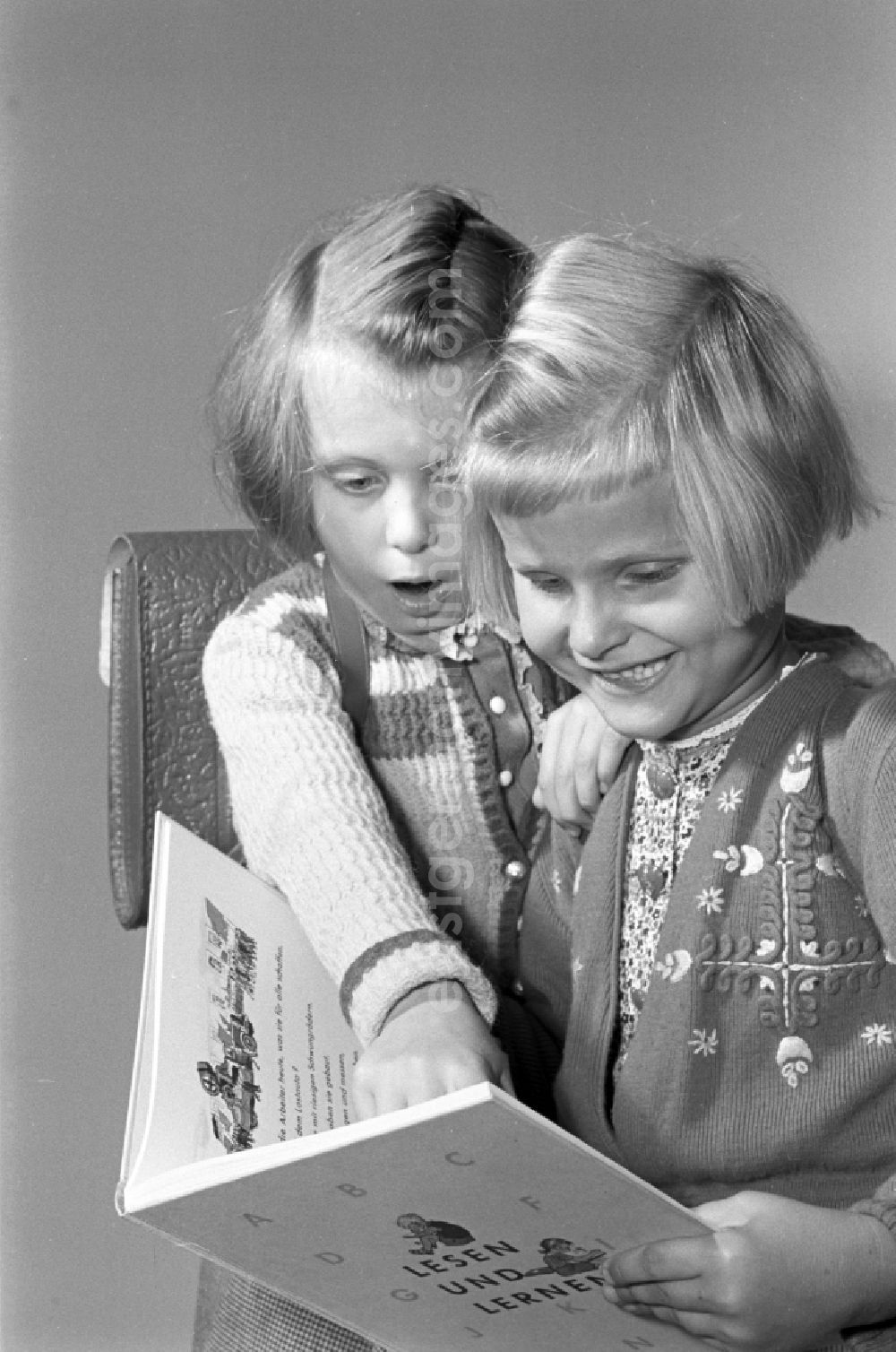 GDR image archive: Dresden - Children on the occasion of the start of school for two young girls enthusiastically looking at a school book on the German language Unsere Fiebel in the district of Altstadt in Dresden in the state of Saxony on the territory of the former GDR, German Democratic Republic