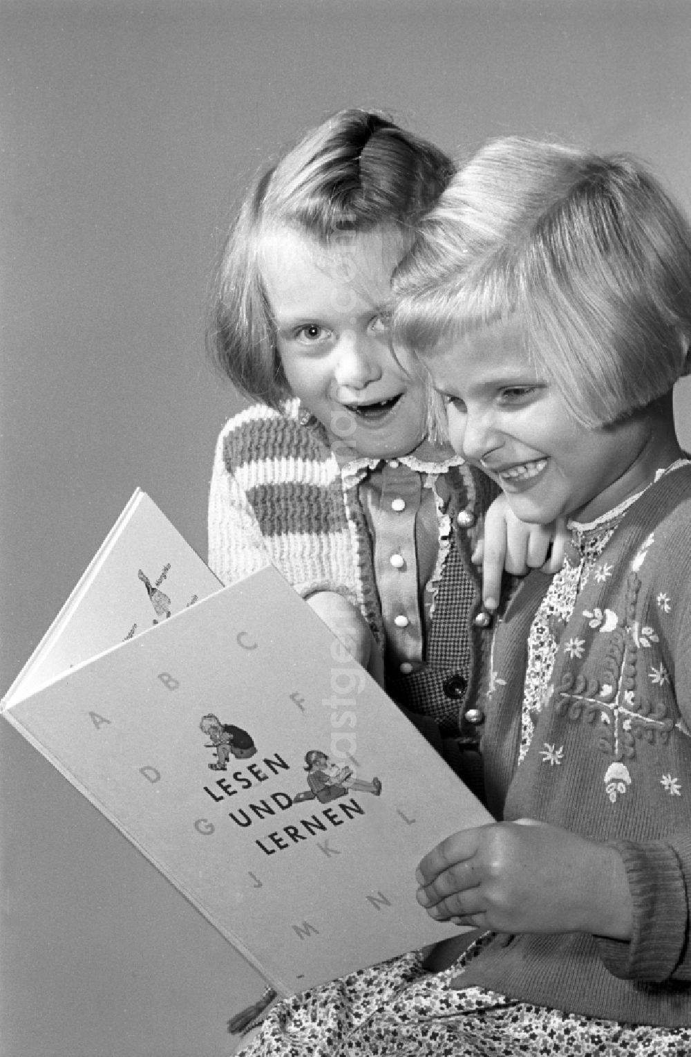 GDR photo archive: Dresden - Children on the occasion of the start of school for two young girls enthusiastically looking at a school book on the German language Unsere Fiebel in the district of Altstadt in Dresden in the state of Saxony on the territory of the former GDR, German Democratic Republic