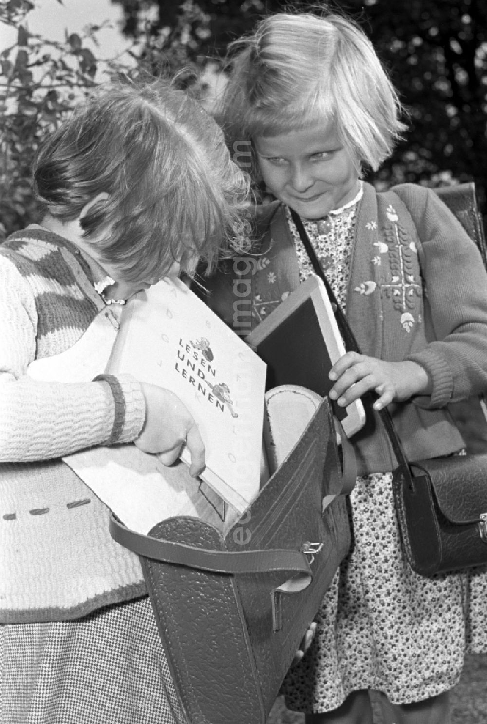Dresden: Children on the occasion of the start of school for two young girls enthusiastically looking at a school book on the German language Unsere Fiebel in the district of Altstadt in Dresden in the state of Saxony on the territory of the former GDR, German Democratic Republic