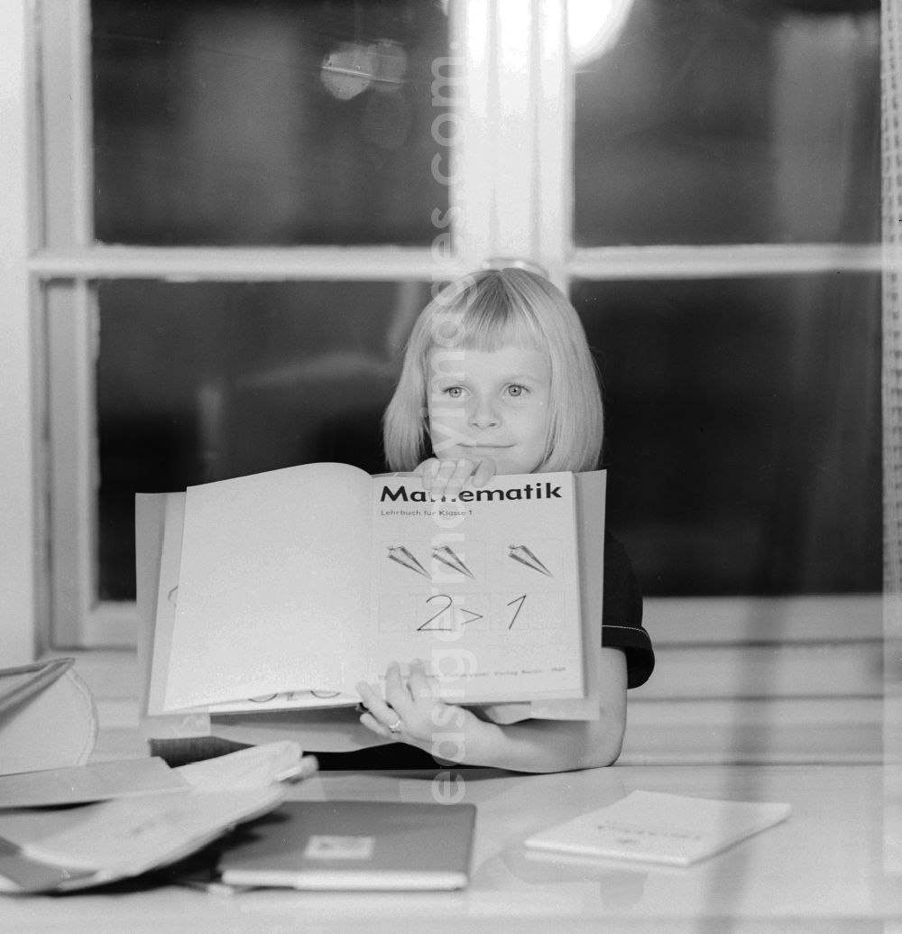 GDR photo archive: Berlin - 1st day of school - girl proudly displays her first math book in Berlin, the former capital of the GDR, the German Democratic Republic
