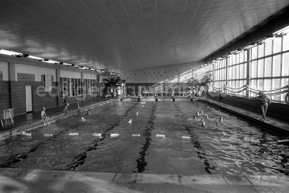 GDR picture archive: Bernburg - Kinder mit Badekappe beim Schwimmunterricht in einem Hallenbad. Ein Schwimmlehrer und eine Schwimmlehrerin geben dabei Anweisungen und Ratschläge.