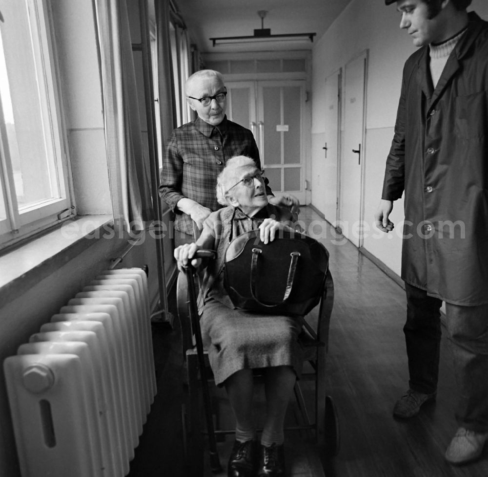 GDR picture archive: Leipzig - A senior citizen in a wheelchair is pushed across a corridor by a woman of the Andersen-Nexoe home in Leipzig in the federal state of Saxony on the territory of the former GDR, German Democratic Republic