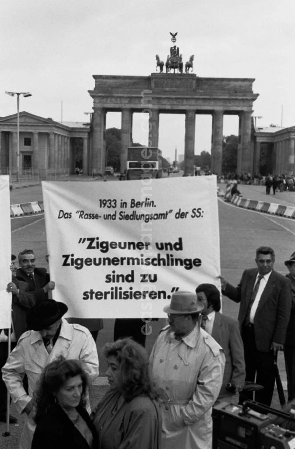 Berlin-Mitte: Sintis und Roma demonstrieren auf dem Pariser Platz vor dem Brandenburger Tor. Demonstranten stehen zusammen und halten Plakat.