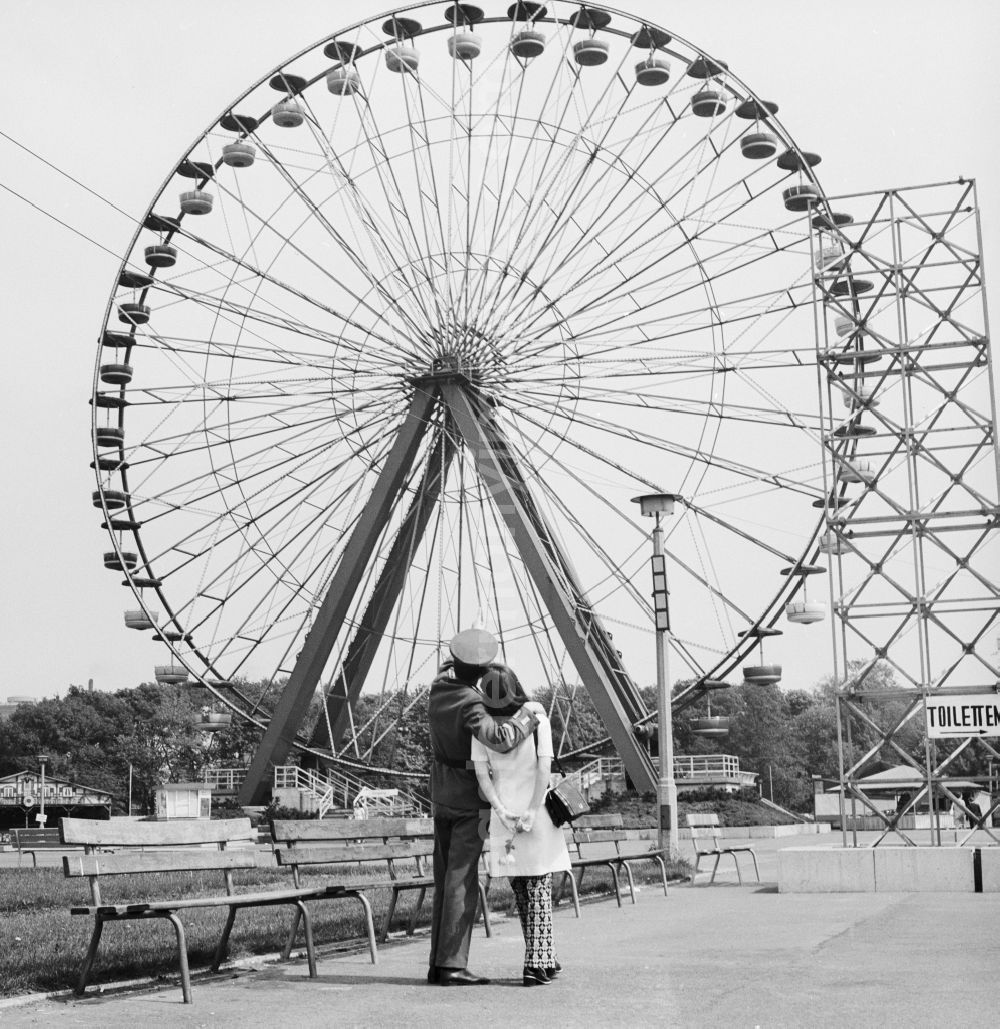 GDR photo archive: Berlin - Treptow - A soldier of the NVA with his wife to visit the Cultural Park Plänterwald in Berlin - Treptow. A special attraction was the Ferris wheel with 36 gondolas that extends 45 meters into the air. The amusement park was opened in 1969. From 1990 to 20