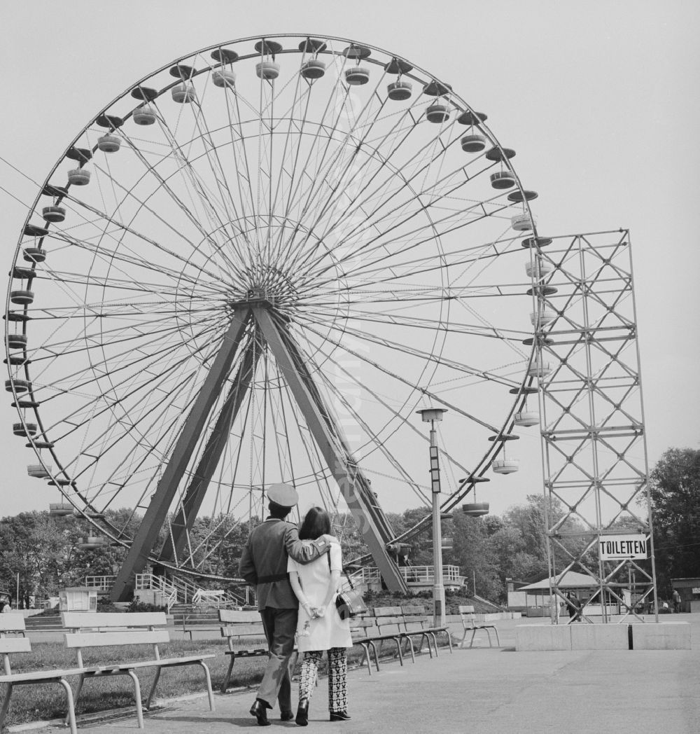 GDR picture archive: Berlin - Treptow - A soldier of the NVA with his wife to visit the Cultural Park Plänterwald in Berlin - Treptow. A special attraction was the Ferris wheel with 36 gondolas that extends 45 meters into the air. The amusement park was opened in 1969. From 1990 to 20