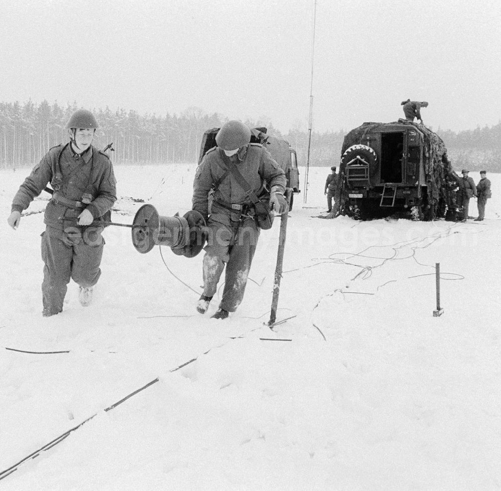 GDR photo archive: Königs Wusterhausen - Soldiers of the 2nd news regiment of the NVA with roll out from news cable during a manoeuvre in winter in Wernsdorf in Koenigs Wusterhausen in the federal state Brandenburg in the area of the former GDR, German democratic republic