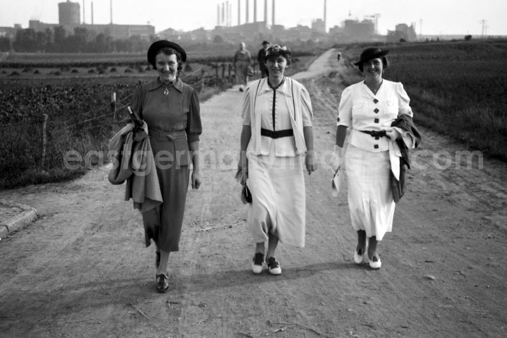 GDR photo archive: Leuna - Three women go for a Sunday walk in Leuna in the federal state Saxony-Anhalt in Germany. In the background the Leuna works