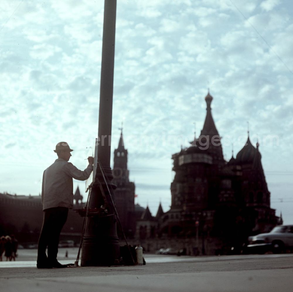 GDR photo archive: Moskau - Ein Maler steht im Gegenlicht an seiner Staffelei und malt den Spasski Turm (l) und die Basilius-Kathedrale (r) am Roten Platz in Moskau.