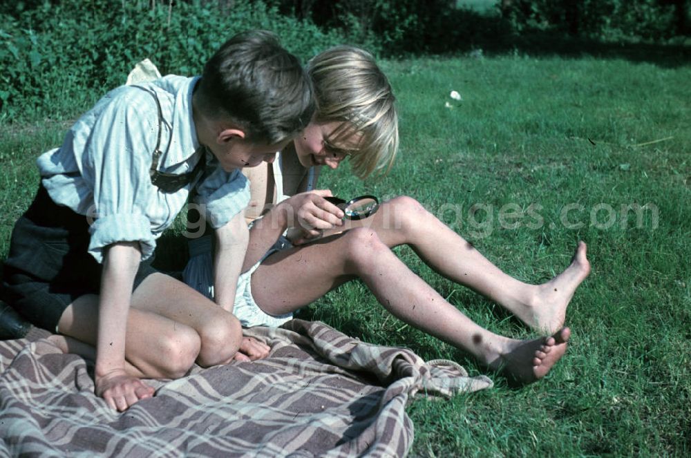 GDR image archive: Leuna - Jungs experimentieren mit einer Lupe auf einer Decke im Freibad. Boys experiment with a magnifier on a blanket in the open-air bath.
