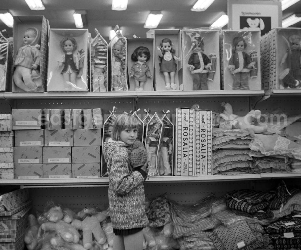 GDR photo archive: Berlin - Ein Mädchen steht in der Spielwarenabteilung im Centrum Warenhaus am Alex in Berlin vor einem Regal mit Puppen.