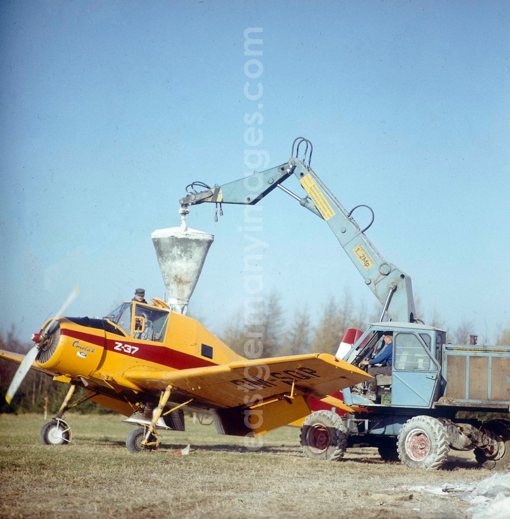 Schlettau: Filling, maintenance and preparation for take-off of an agricultural aircraft of type Let Z-37 Cmelak with sign called DM-SOP of the agricultural flight operation of the state airline INTERFLUG on a strip of fields of an LPG - agricultural production cooperative to a spray flight for fertilization and pest control in the district Neu-Amerika in Schlettau at Erzgebirge in the state Saxony on the territory of the former GDR, German Democratic Republic