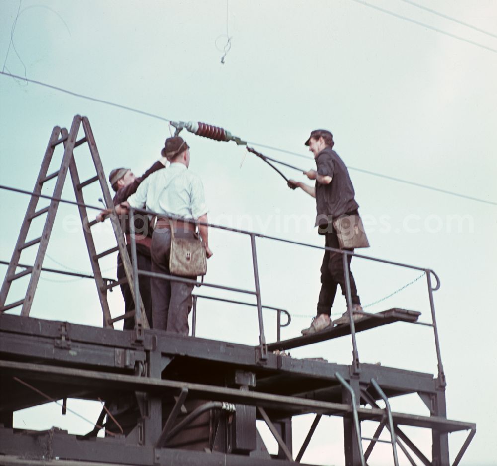 GDR photo archive: Halle (Saale) - Work on the assembly of copper overhead lines - power lines on the rails and over the track systems on the railway line of the DR Deutsche Reichsbahn on the outskirts in Halle (Saale) in the state Saxony-Anhalt on the territory of the former GDR, German Democratic Republic