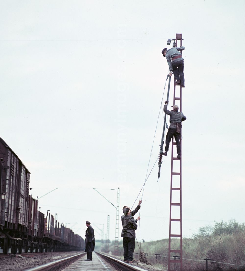 GDR photo archive: Halle (Saale) - Work on the assembly of copper overhead lines - power lines on the rails and over the track systems on the railway line of the DR Deutsche Reichsbahn on the outskirts in Halle (Saale) in the state Saxony-Anhalt on the territory of the former GDR, German Democratic Republic