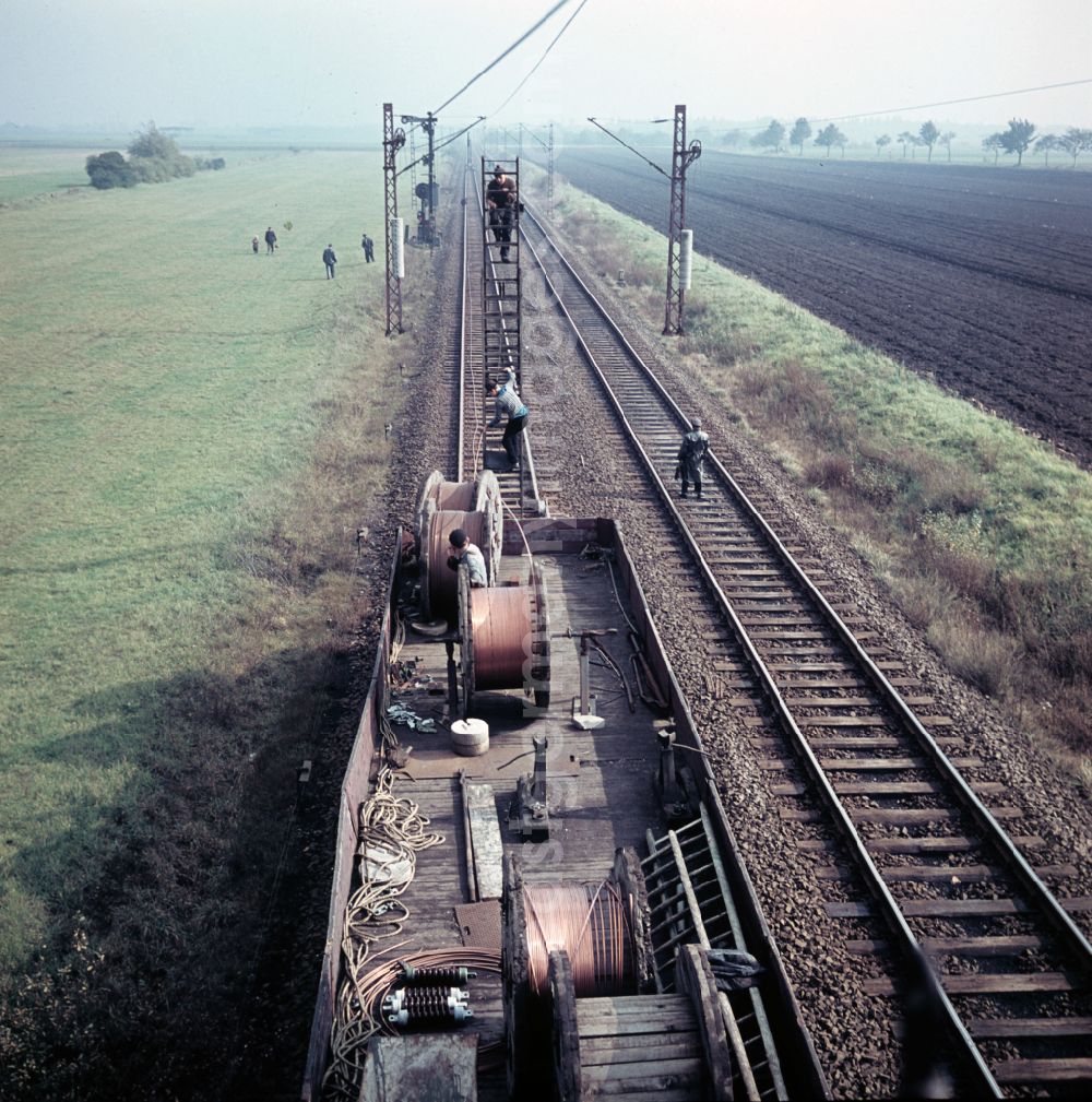 GDR picture archive: Halle (Saale) - Work on the assembly of copper overhead lines - power lines on the rails and over the track systems on the railway line of the DR Deutsche Reichsbahn on the outskirts in Halle (Saale) in the state Saxony-Anhalt on the territory of the former GDR, German Democratic Republic