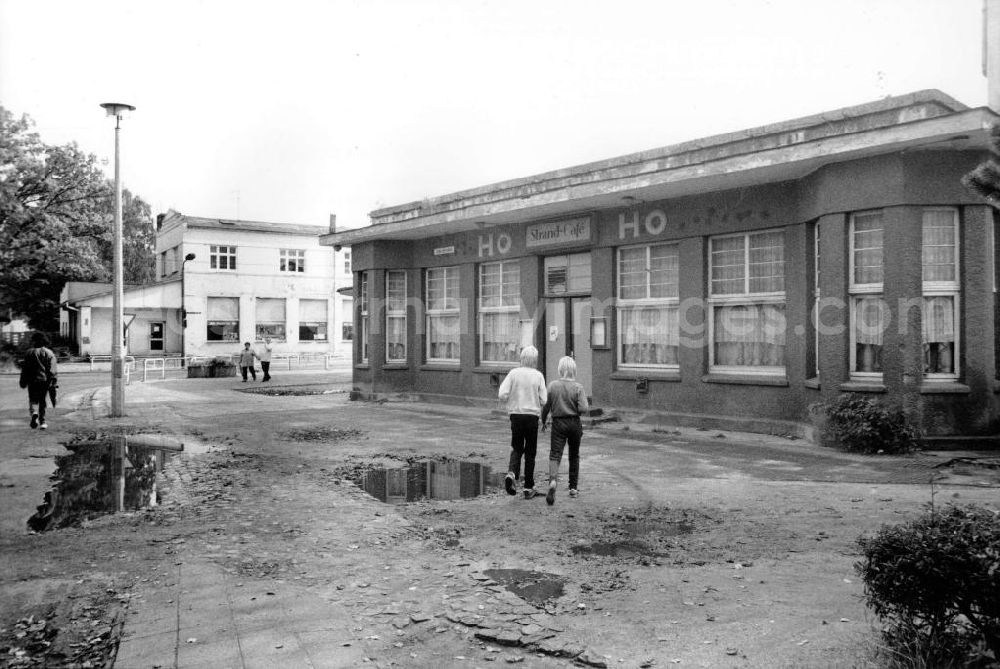 GDR photo archive: Kühlungsborn - Einwohner vor einem HO Strandcafe. Schlaglöscher auf der Strasse und dem Gehweg sind mit Regenwasser gefüllt. Das Ostseebad Kühlungsborn war mit ca. 150.00