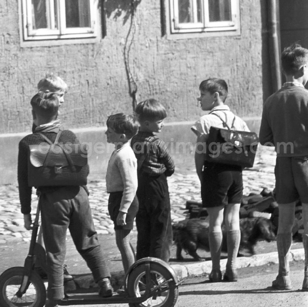 GDR picture archive: Neuruppin - Kinder / ein Kind mit einem Roller auf einer Straße. Einige Jungen mit Schulranzen / Schultasche. Orlamünde gehört zum heutigen Saale-Holzland-Kreis und liegt an der Mündung der Orla in die Saale. Bestmögliche Qualität nach Vorlage!