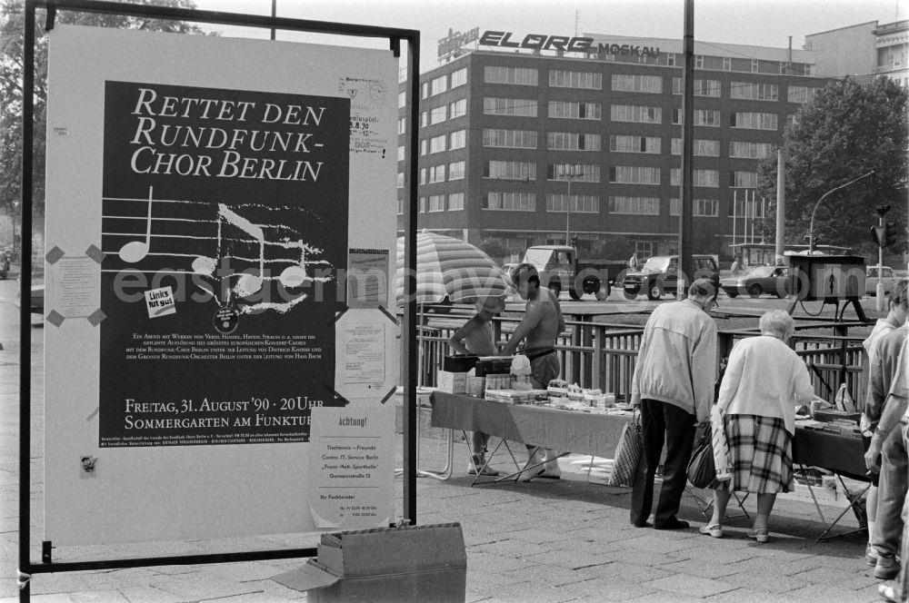 GDR image archive: Berlin - A poster with the words Save the Rundfunk-Chor Berlin stands at the Frankfurter Tor in Berlin - Friedrichshain. In the background, passers-by are standing at a stall