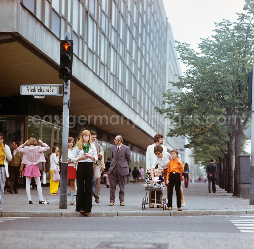 GDR image archive: Berlin - Passanten stehen an einer roten Ampel an der Kreuzung Friedrichstraße / Ecke Unter den Linden in Berlin-Mitte, im Hintergrund die Ladenpassage des Grand-Hotel.