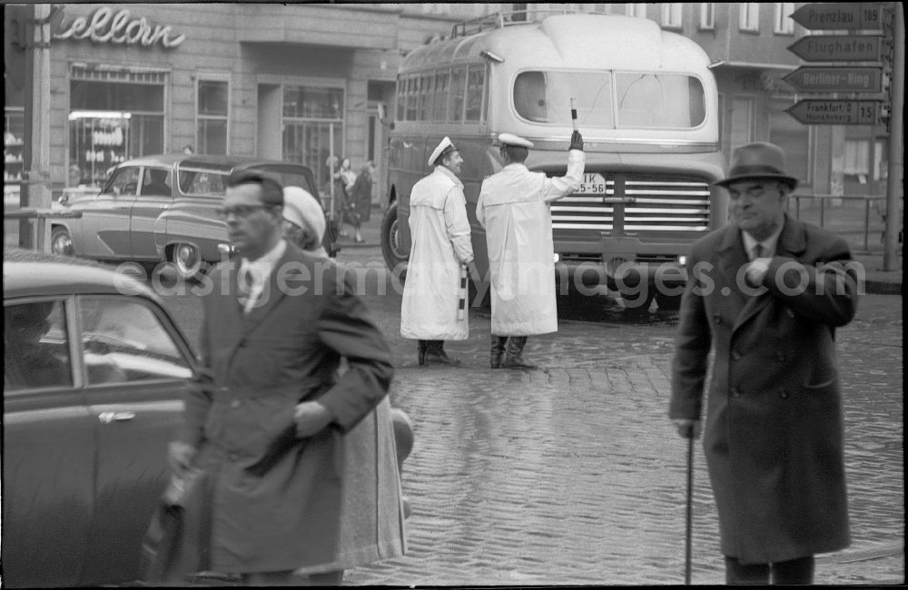 GDR photo archive: Berlin - Traffic policeman of the DVP German People's Police regulates the traffic situation with cars - motor vehicles and pedestrians on the road at Schoenhauser Allee crossing Eberswalder Strasse in the district of Prenzlauer Berg in the district Prenzlauer Berg in Berlin East Berlin on the territory of the former GDR, German Democratic Republic