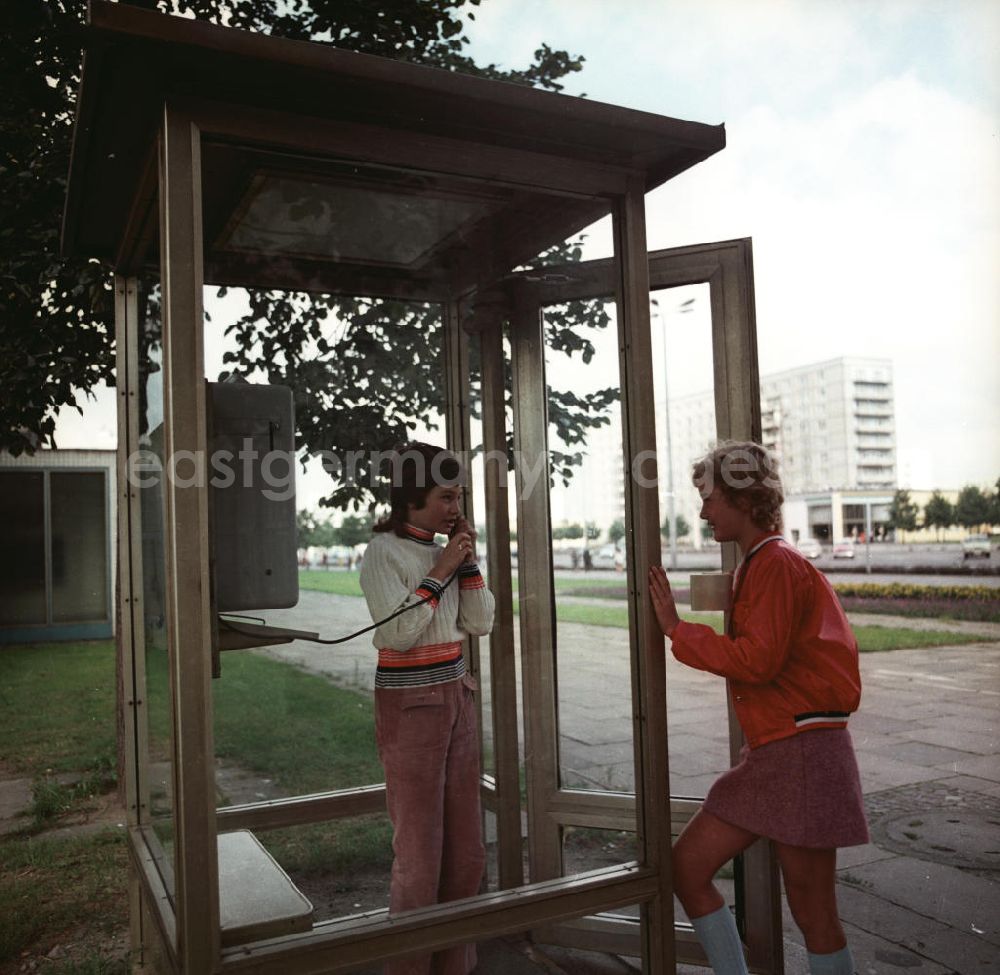 GDR picture archive: Potsdam - Zwei Mädchen benutzen ein modernes Telefonhäuschen / Telefonzelle in Potsdam.