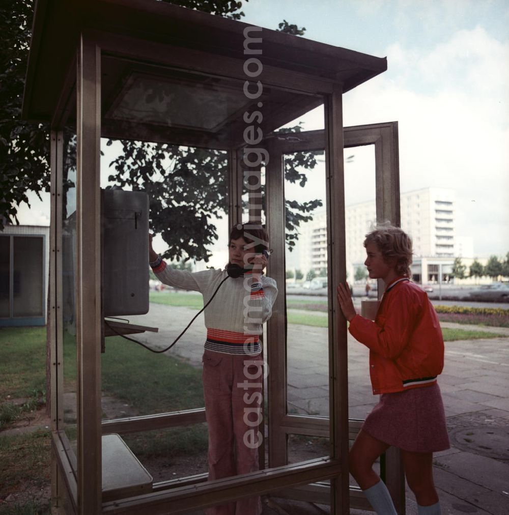 Potsdam: Zwei Mädchen benutzen ein modernes Telefonhäuschen / Telefonzelle in Potsdam.