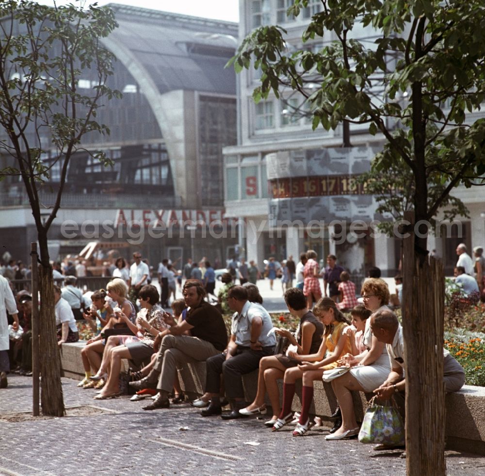 GDR photo archive: Berlin - Mitte - Tourists sitting on the world clock in front of the S-train station Alexanderplatz in Berlin - Mitte. In the right background is the Berolina house to see