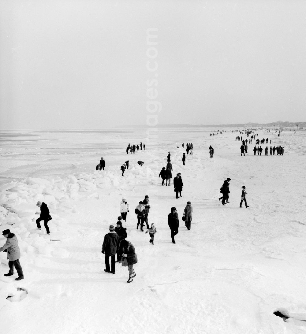 GDR picture archive: Warnemünde - Tourists walk on the frozen and snow-covered Baltic Sea in Warnemuende in the federal state Mecklenburg-Western Pomerania on the territory of the former GDR, German Democratic Republic