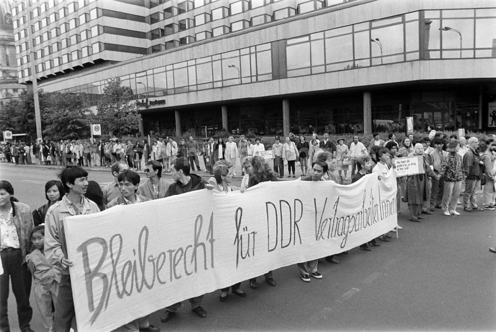 Berlin: Vietnamese guest workers - contract workers on Karl-Liebknecht-Strasse in front of the palace hotel with protest poster and banner slogan Right to stay for GDR contract workers in the Mitte district of Berlin East Berlin on the territory of the former GDR, German Democratic Republic