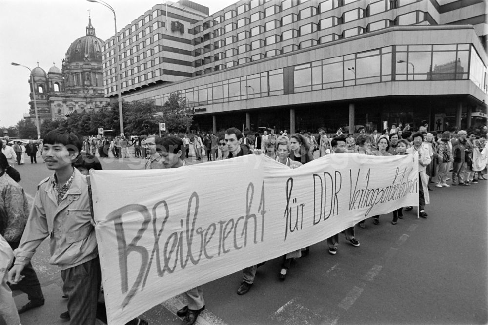 GDR image archive: Berlin - Vietnamese guest workers - contract workers on Karl-Liebknecht-Strasse in front of the palace hotel with protest poster and banner slogan Right to stay for GDR contract workers in the Mitte district of Berlin East Berlin on the territory of the former GDR, German Democratic Republic