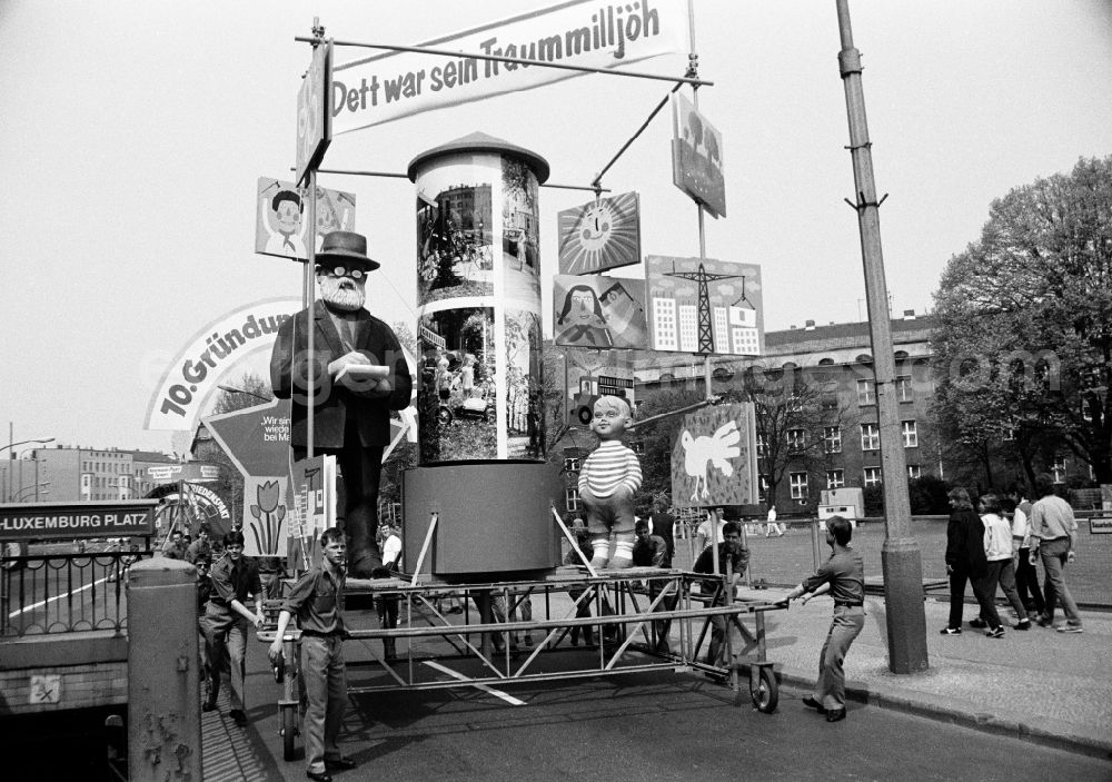 GDR picture archive: Berlin - Protest poster and banner slogan for May 1st mounted on pushcarts pushed by young FDJ members on the street at the intersection of Karl-Liebknecht-Strasse - Memhardstrasse in the Mitte district of Berlin East Berlin on the territory of the former GDR, German Democratic Republic