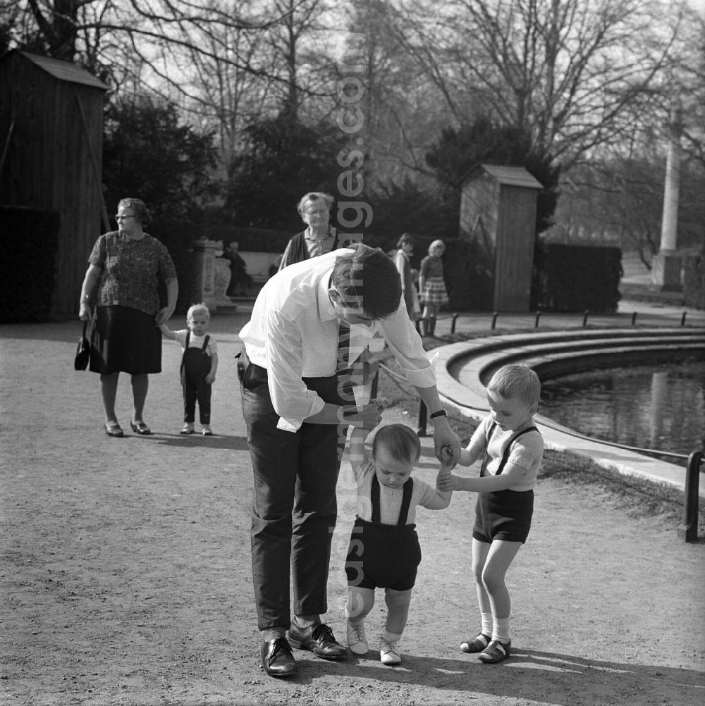 Potsdam: Ein Vater unterstützt seinen jüngeren Sohn bei dessen Gehversuchen in einem Park in Potsdam. A father supports his younger son at his first attempts at walking in a park in Potsdam.