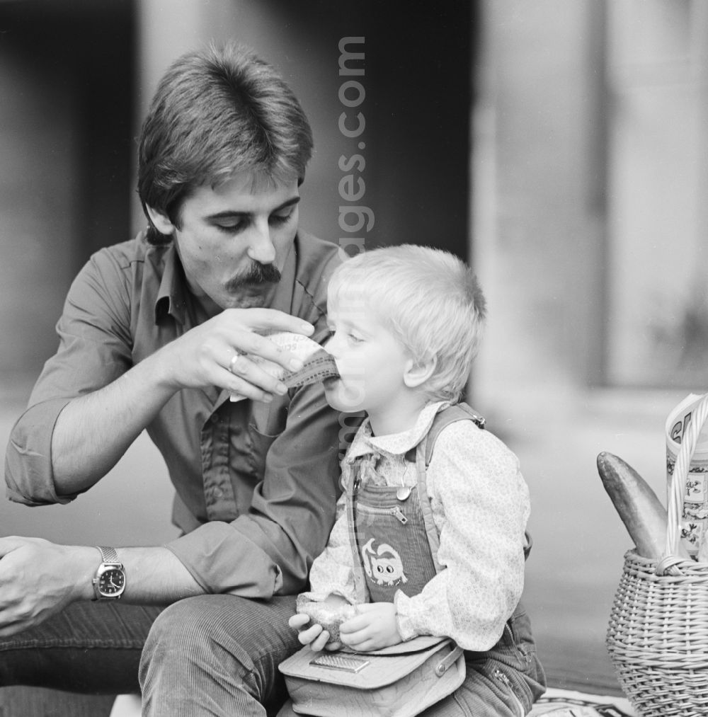 Berlin: Father sitting with his child on a bench and eat a sandwich in Berlin, the former capital of the GDR, the German Democratic Republic