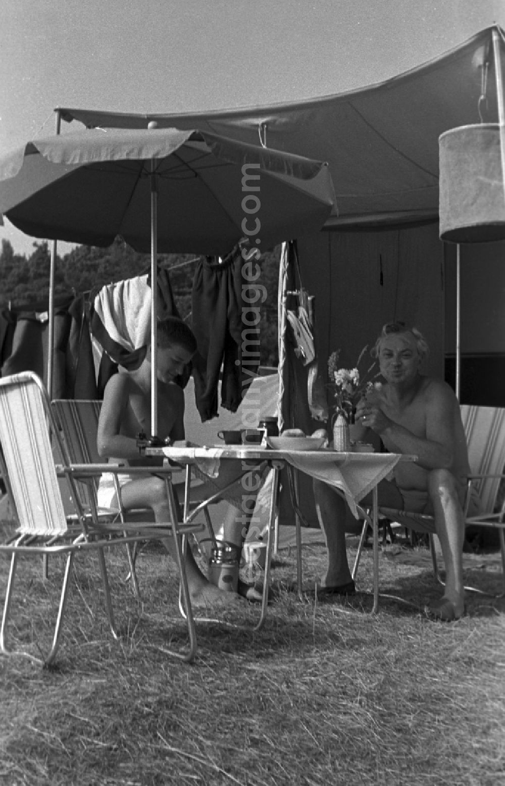 GDR photo archive: Neuruppin OT Stendenitz - Father and son sitting on camping chairs under an awning at the campsite on Tornowsee in Brandenburg. Family camping holidays at Rottstielfließ on Tornowsee in Brandenburg