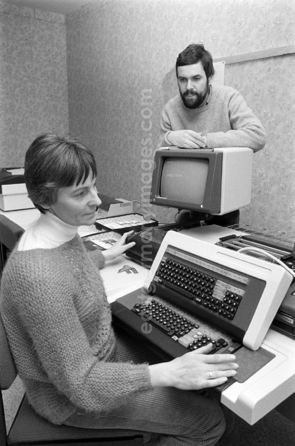 GDR photo archive: Berlin - Employee at the project planning in the VEB Baukombinat Koepenick in the district Treptow-Koepenick in Berlin, the former capital of the GDR, German Democratic Republic. Woman sits in front of a Robotron computer and man stands behind a screen / monitor