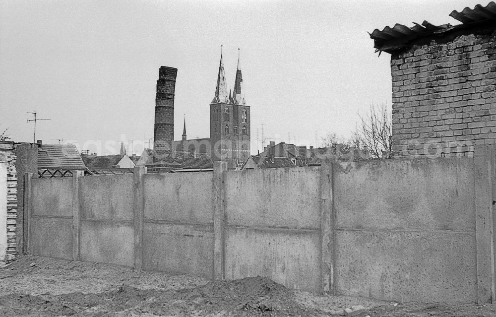 GDR image archive: Stendal - Decaying masonry in front of the facade and roof structure of the sacred building of the church of the double towers of St. Mary's Church in Stendal in GDR