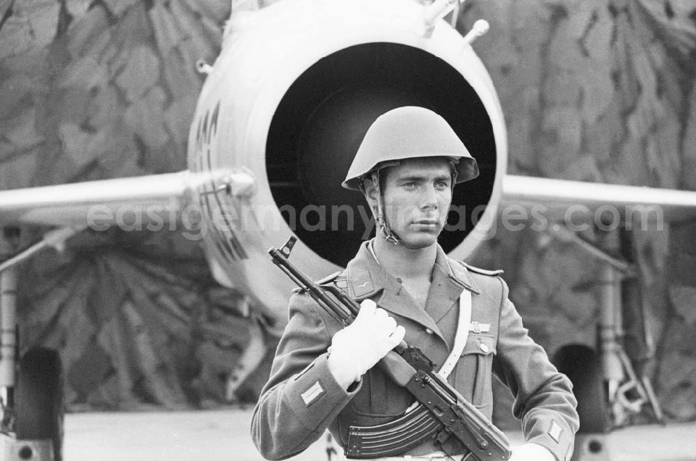 GDR picture archive: Peenemünde - Guardsman with a Kalashnikov AK-47 before a staff MIG-21 fighter squadron of 9 in Peenemuende in Mecklenburg-Western Pomerania in the field of the former GDR, German Democratic Republic