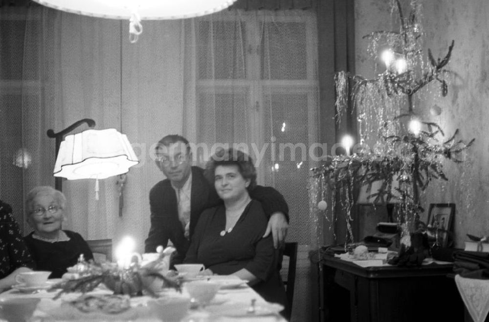 GDR image archive: Leipzig - Zum Weihnachtsfest sitzt eine Familie an der Kaffeetafel, die mit dem guten Geschirr und einem Stollen gedeckt ist. Ein spärlich bewachsener, mit viel Lametta geschmückter Weihnachtsbaum schmückt den Gabentisch.