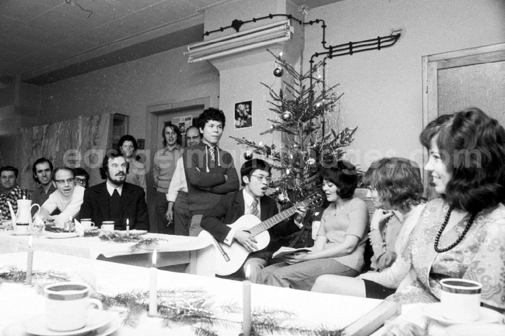 GDR picture archive: Berlin - The staff at VEB Messelektronik MEB at the company Christmas party. A Vietnamese contract worker plays a guitar and sings in the Friedrichshain district of Berlin in the district Friedrichshain in Berlin, the former capital of the GDR, German Democratic Republic