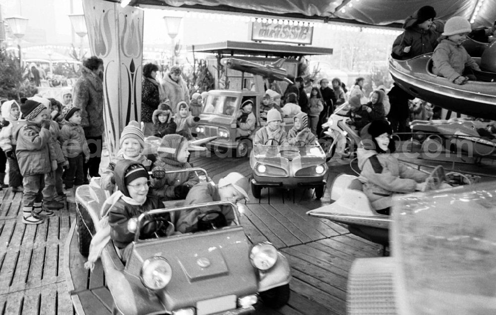 GDR photo archive: Berlin - Traditional Christmas market as a special experience area for children and young people at the end of the yearmit Kindern in einem Fahrzeug- Karussel in the district Mitte in Berlin Eastberlin on the territory of the former GDR, German Democratic Republic