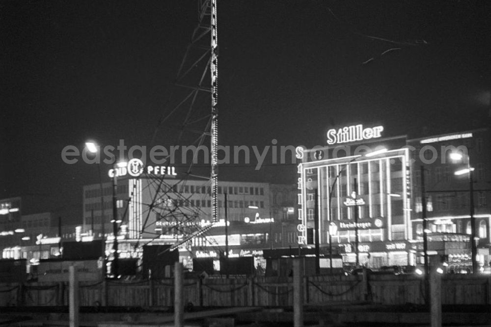 GDR photo archive: Berlin - Leuchtreklame wohin das Auge blickt - als Schaufenster des Westens und Symbol des Wirtschaftswunders erstrahlt der Kurfürstendamm, Westberlins wichtigste Flaniermeile, auch abends in hellem Licht. An der Rückseite des Metallträgers im Vordergrund des Bildes heißt es in einer Leuchtreklame Berlin spielt. In den 5