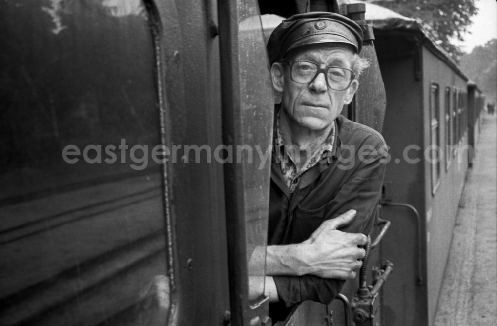 Putbus: Engine driver in the driver's cab of the train on the station grounds of the Deutsche Reichsbahn narrow-gauge railway in Putbus, Mecklenburg-Western Pomerania in the territory of the former GDR, German Democratic Republic