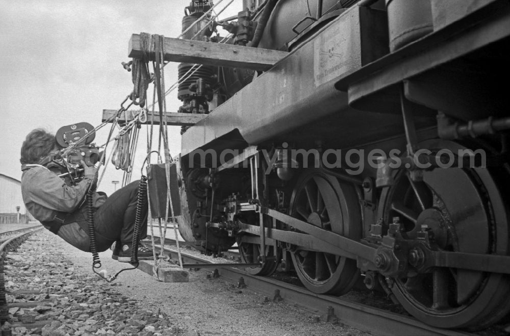 GDR image archive: Putbus - Cameraman filming the track rod of the chassis of a steam locomotive of the Ruegensche Baederbahn - Rasender Roland train on the station premises of the Deutsche Reichsbahn narrow-gauge railway in Putbus, Mecklenburg-Western Pomerania on the territory of the former GDR, German Democratic Republic