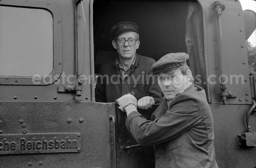 GDR image archive: Putbus - Engine driver in the driver's cab of the train on the station grounds of the Deutsche Reichsbahn narrow-gauge railway in Putbus, Mecklenburg-Western Pomerania in the territory of the former GDR, German Democratic Republic