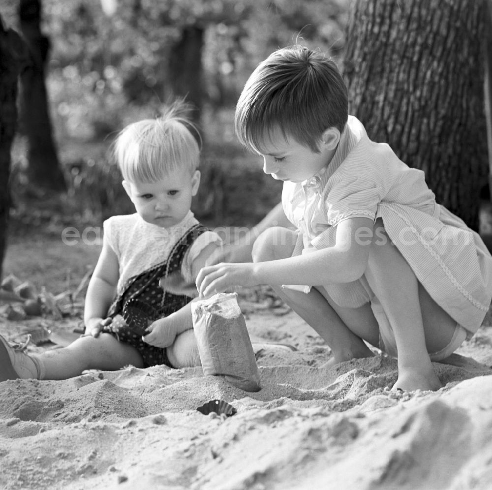 GDR picture archive: Warnemünde - Two children playing in the sand in Warnemünde in Mecklenburg - Western Pomerania