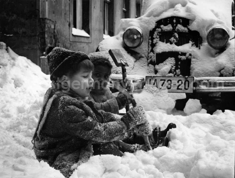 GDR photo archive: Berlin - Two children sit in the street edge in the snow in Berlin, the former capital of the GDR, German democratic republic