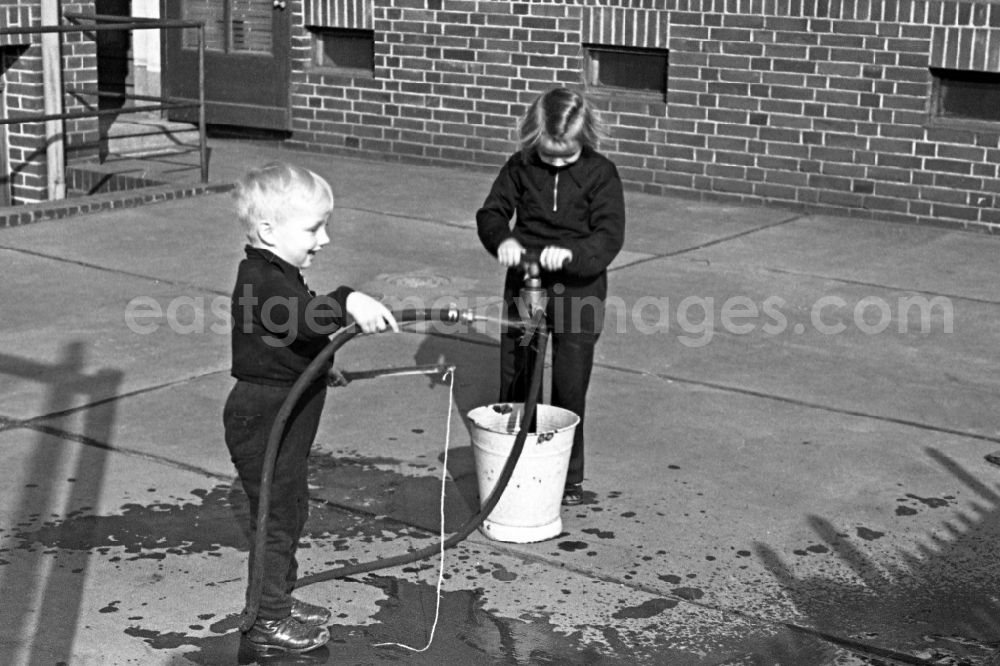 Merseburg: Two children play in the inner courtyard with a water hose in Merseburg in the federal state Saxony-Anhalt in Germany