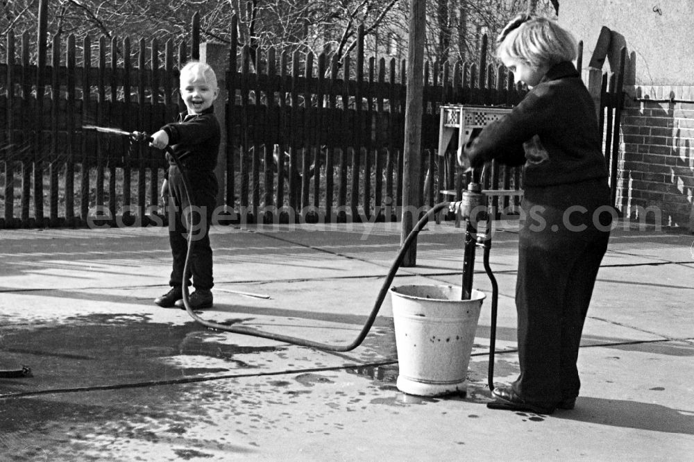 GDR image archive: Merseburg - Two children play in the inner courtyard with a water hose in Merseburg in the federal state Saxony-Anhalt in Germany